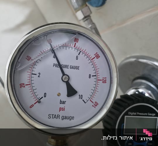 מד לחץ מים על קיר עם צינור